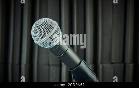 Microphone à vue latérale monté sur le support du microphone et sur la mousse acoustique arrière-plan en tons gris Banque D'Images