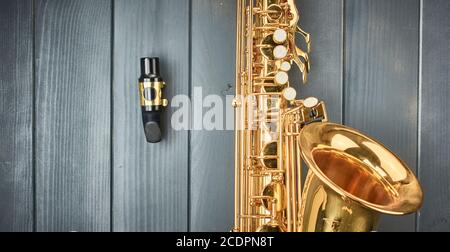 Embout buccal saxophone démonté du corps de l'instrument, avec garde dentaire et pince dorée, sur bois gris Banque D'Images