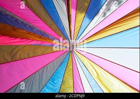 Parasol rose ouvert géométrique isolé et multicolore contre le ciel lumineux donne l'impression d'être en été. Banque D'Images