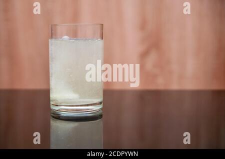 le comprimé effervescent se dissout dans un verre d'eau sur un table noire Banque D'Images