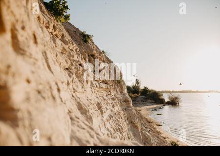 Avalez les nids dans le sable sur le sommet d'une falaise et des hirondelles volantes contre le ciel du coucher du soleil. Magnifique coucher de soleil sur le lac. Mise au point sélective Banque D'Images