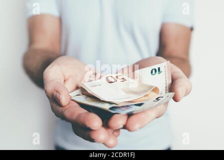 gros plan des mains d'un homme caucasien offrant ou remettant argent à quelqu'un d'autre Banque D'Images