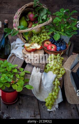 L'automne encore la vie. Fruits et baies. Pommes, raisins, fraises, prunes sur une table en bois. Style campagnard. Nourriture saine et inactive en vitamines. Récolte de fruits. Banque D'Images