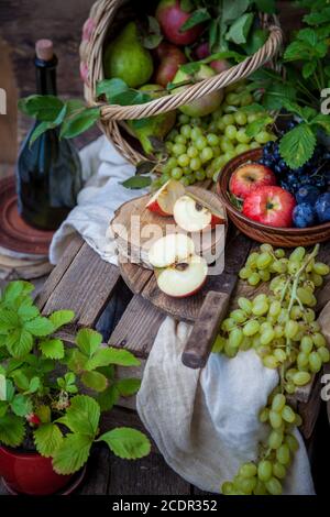 L'automne encore la vie. Fruits et baies. Pommes, raisins, fraises, prunes sur une table en bois. Style campagnard. Nourriture saine et inactive en vitamines. Récolte de fruits. Banque D'Images