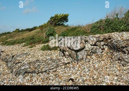 Les roches sont fixées à l'aide d'un filet métallique au-dessus de la ligne de bardeau pour empêcher l'érosion. East Wittering / West Wittering Beach, West Sussex, Angleterre. Banque D'Images