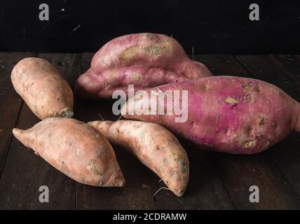 Patates douces rouges crues sur une table rustique en bois Banque D'Images