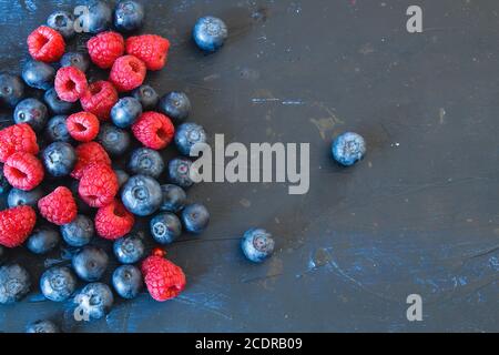 Framboises et bleuets sur fond bleu foncé Banque D'Images