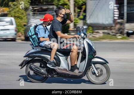 THAÏLANDE, JUL 18 2020, UN homme conduit une moto et protège ses yeux de ses mains contre la lumière du soleil. Banque D'Images