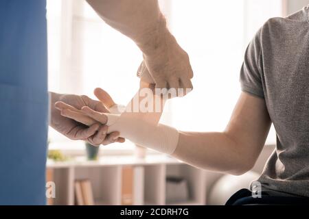 Mains du clinicien dans un emballage uniforme paume droite et poignet de patient malade Banque D'Images