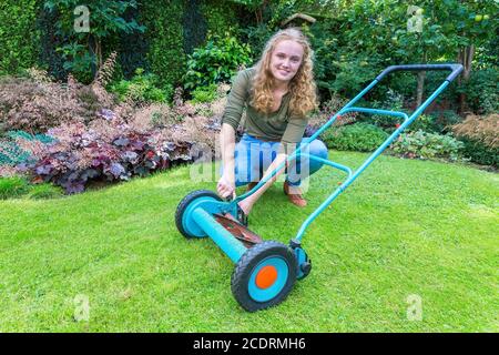 Jeune femme caucasienne réparant la tondeuse dans le jardin Banque D'Images