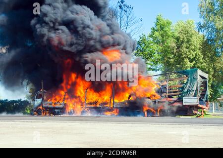 Chariot en feu avec fumée noire sur la route Banque D'Images