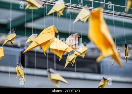 Jaune Orange Origami grues de papier qui pèsent sur les oiseaux de l'architecture industrielle arrière-plan flou Banque D'Images