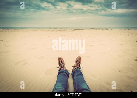 Première personne perspective de l'homme jambes en jeans sur le plage d'automne Banque D'Images