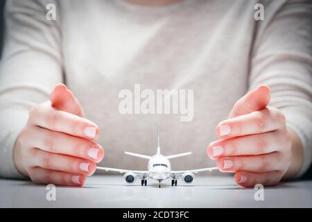 Modèle d'avion entouré de mains dans un geste de protection. Sécurité de l'industrie aéronautique, assurance Banque D'Images