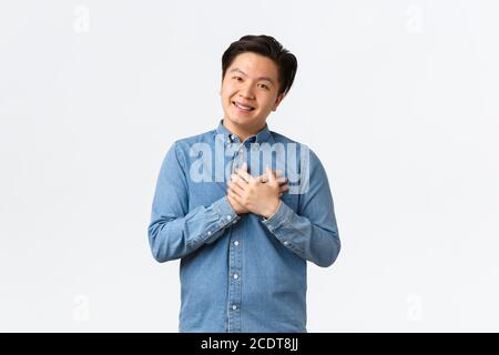 Jeune homme d'affaires asiatique plein d'espoir et heureux commençant sa propre startup, tenant les mains sur le cœur comme reconnaissant pour les investissements de personnes, prenant soin de clients Banque D'Images