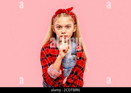 Enfant fille regardant l'appareil photo, faisant l'enseigne shh Banque D'Images