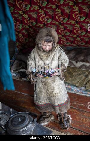 Un jeune Nenet jouant avec un jouet à l'intérieur d'un chum (tente traditionnelle couverte de peaux de rennes), Yamalo-Nenets Autonomous Okrug, Russie Banque D'Images