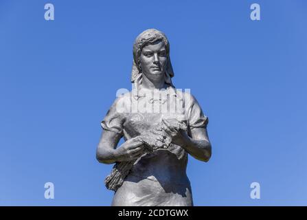 La statue d'un agriculteur collective sur un piédestal contre un ciel bleu. Banque D'Images