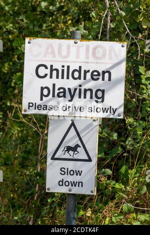 Enfants jouant, attention, s'il vous plaît conduire lentement, ralentir, chevaux, panneaux à Great Wakering, près de Southend, Essex, Royaume-Uni. Rural, route de campagne Banque D'Images