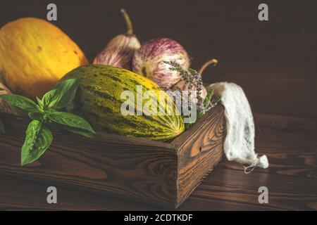 Melon, basilic, menthe, graffiti pourpre aubergines, oignon et basilic frais vert dans une boîte en bois sur fond de bois vintage en rus Banque D'Images