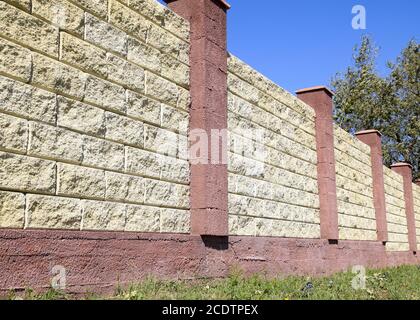Clôture faite de briques et de plâtre décoratif. Clôture jaune rouge avec éléments. L'escrime de haut et beau Banque D'Images