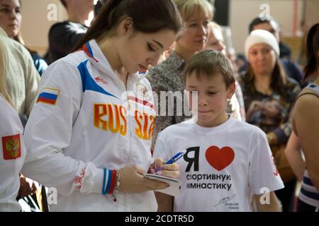 Moscou, Russie. Le 25 octobre 2014, la championne olympique Aliya Mustafina donne un autographe à un jeune gymnaste lors d'une classe de maître dans la salle de sport Dynamo du stade olympique de Moscou, Russie. L'inscription sur le short se lit comme suit : « J'aime la gymnastique » Banque D'Images