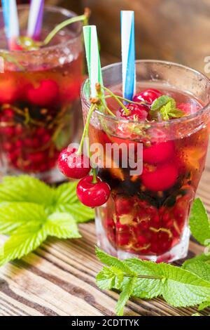 Verres de boisson rafraîchissante aromatisés aux fruits frais et décorés avec des cerises recouvertes de gouttes de rosée Banque D'Images