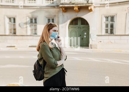 Fille avec masque parlant au téléphone dans la rue Banque D'Images