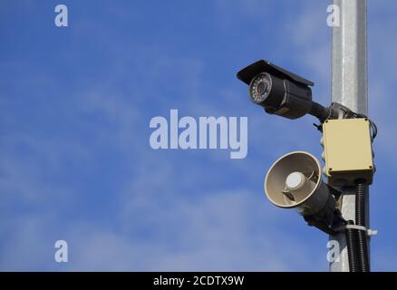 Caméra CCTV et alarme de haut-parleur sur un poteau contre un ciel bleu. Banque D'Images