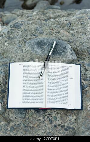 Bible hébraïque ouverte - TANAKH (Torah, Neviim, Ketuvim - la Loi, les prophètes, les écrits) avec plume de fontaine plein air. Isolé sur fond de pierres. Banque D'Images