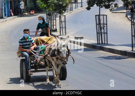 Gaza. 29 août 2020. Les Palestiniens portant des masques faciaux se trouvent dans une rue de la ville de Gaza, le 29 août 2020, à bord d'une voiturette à âne. Credit: Rizek Abdeljawad/Xinhua/Alamy Live News Banque D'Images