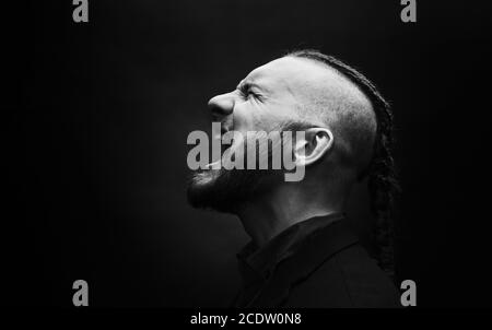 L'homme avec des dreadlocks cris de rage, ressemble à un viking, coupe Iroquois Banque D'Images