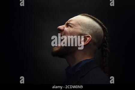 L'homme avec des dreadlocks cris de rage, ressemble à un viking, coupe Iroquois Banque D'Images