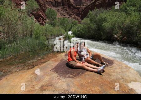 Deux jeunes femmes se reposent près de Tapeats Creek lors d'une excursion de randonnée de plusieurs jours dans le parc national du Grand Canyon, en Arizona, en été. Banque D'Images