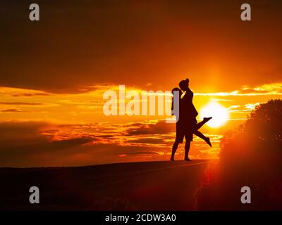 Couple romantique à la campagne au coucher du soleil avec le soleil et un arbre Banque D'Images