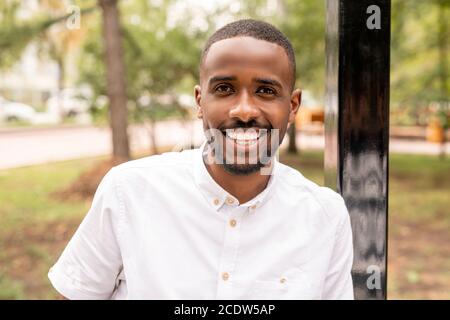 Jeune homme joyeux d'origine africaine vous regardant avec un sourire blanc éclatant Banque D'Images