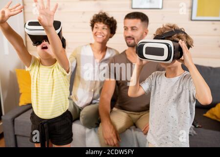 Un petit garçon et une petite fille dans un casque vr regardant des choses curieuses sur l'affichage virtuel Banque D'Images