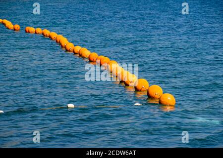 Bouées d'orange sur une corde dans la mer. Clôture pour la natation en mer Banque D'Images