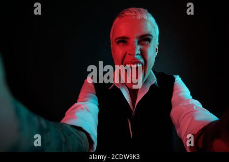 Jeune femme furieuse aux cheveux blonds courts exprimant l'agression et crier Banque D'Images