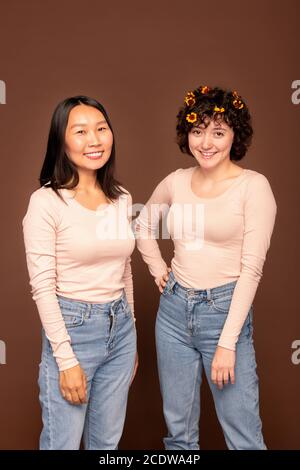 Deux jeunes femmes interculturelles heureuses en pull-overs blanc et bleu jeans Banque D'Images