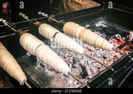Trdelnik, une pâtisserie traditionnelle typiquement tchèque, est cuite sur de longues bâtonnets au feu de charbon ouvert Banque D'Images