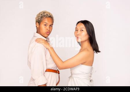 Jeune femme asiatique avec de longs cheveux foncés gardant la main sur Épaule de fille africaine Banque D'Images