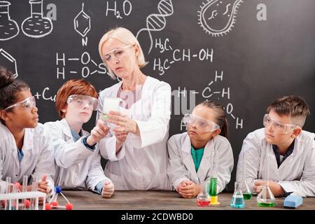 Professeur de chimie en blancoat montrant le mélange de deux produits chimiques substances Banque D'Images