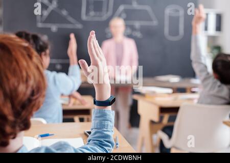 Armes d'élèves intelligents prêts à répondre à la question de l'enseignant par tableau noir Banque D'Images
