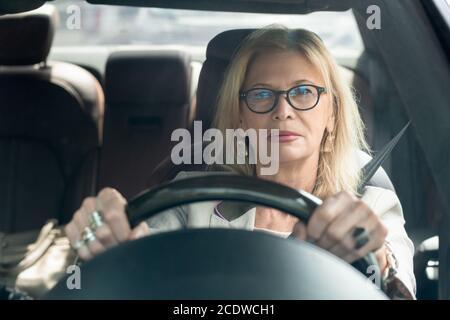 Blonde réussie femme d'affaires élégante en lunettes de vue conduisant au travail Banque D'Images