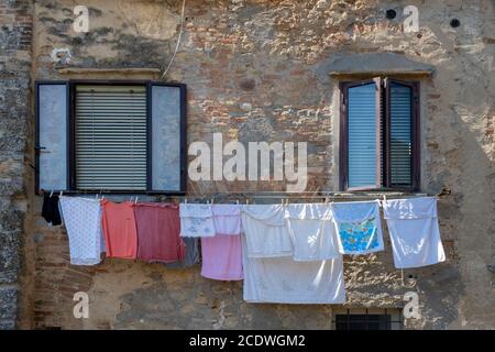 Vêtements suspendus sous une fenêtre sur un mur de briques Banque D'Images