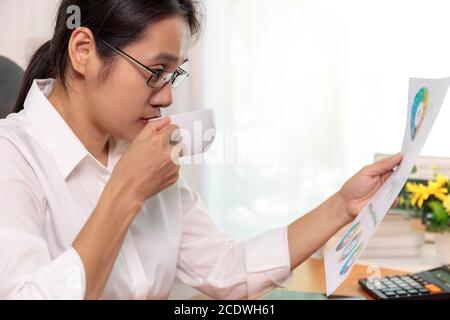 Gros plan femmes d'affaires asiatiques travaillant à domicile graphique de rapport d'analyse. Les gens d'affaires qui cherchent un plan de travail sont à portée de main. Banque D'Images