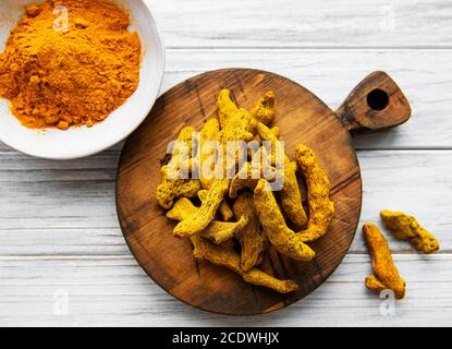 Poudre curcuma jaune et racines sèches sur fond de bois. Banque D'Images