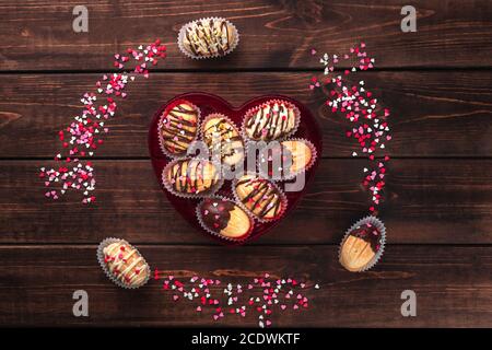 cadre fait de biscuits faits maison de noix en forme de crème, glaçage au chocolat sur table en bois comme fond, rouge, rose et blanc sucre saupoudrer coeurs, déc Banque D'Images