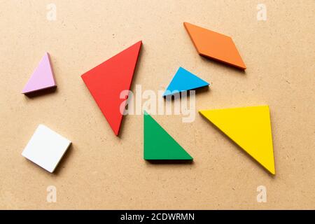 Casse-tête en forme de tangram de couleur dans une pièce qui attend de terminer la forme sur fond de bois Banque D'Images